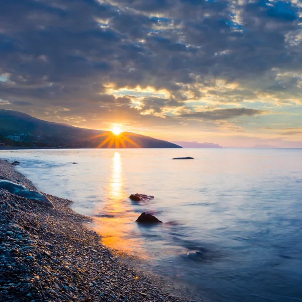 Pôr-do-sol dramático sobre uma costa rochosa — Fotografia de Stock