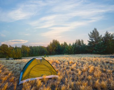 Gün batımında çayırların arasında küçük bir turistik çadır