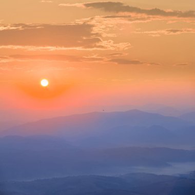 Dağ sırtı silueti gün doğumunda mavi sisli, sabah erken saatlerde dağ vadisi manzaralı