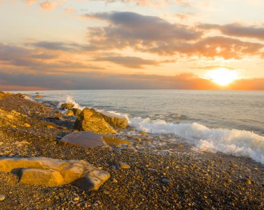 Güneşin doğuşunda taşlı deniz plajı