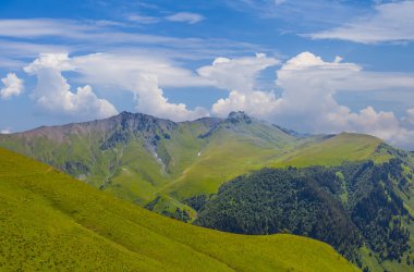 Bulutlu gökyüzünün altındaki yeşil dağ vadisi, doğal seyahat geçmişi