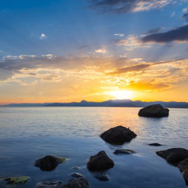 Dramatik günbatımında taşlı sessiz deniz koyunda