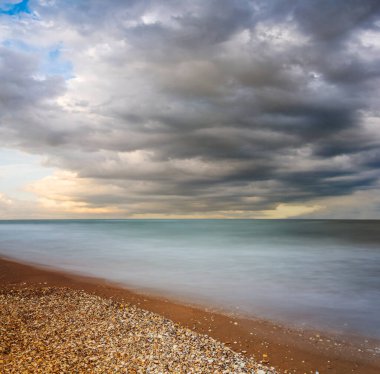 Kumlu deniz plajı yoğun bulutlu gökyüzü altında, uzun süre sessiz deniz manzarası