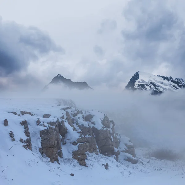 濃い霧と雲の中の雪に覆われた山 — ストック写真