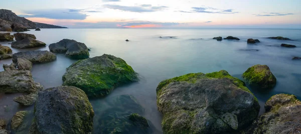 夕阳西下 平静的海湾里 布满了石头 — 图库照片