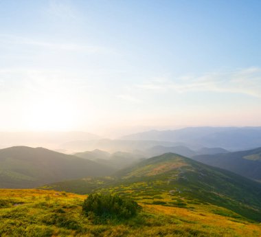 Yeşil dağ vadisi mavi sisli gün doğumunda, sabahın erken saatlerinde dağ manzaralı