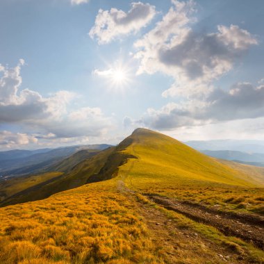 Parlak güneşin altında yeşil çimlerle kaplı dağ sırtı, yaz doğal dağ manzarası