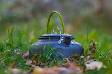 Çimenlerdeki küçük çaydanlık, doğal kamp arka planı.