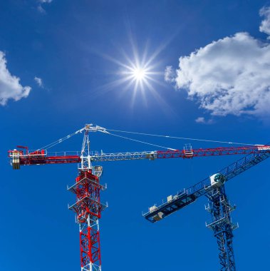Mavi bulutlu arka planda bir çift kule vinci