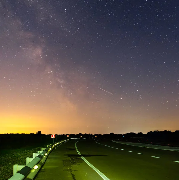 asphalt road turn  under dark starry sky with milky way, night transportation infrastructure scene