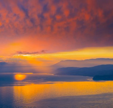 Deniz koyunda dağ kıyısında dramatik günbatımında