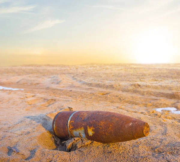 rusty bomb lie among sandy desert at the sunset, military war scene