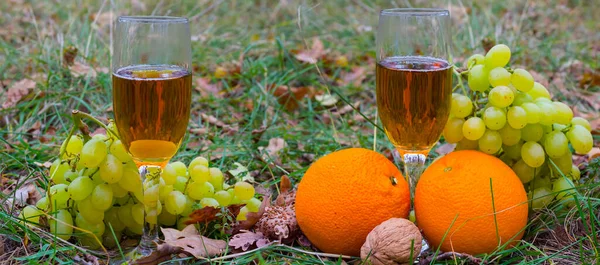 closeup wine glass with  fruit heap on forest glade, outdoor food and drink natural background