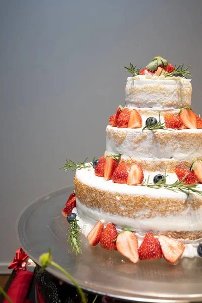 A three-tiered wedding cake with plenty of strawberries