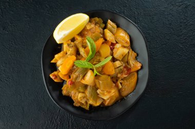 Siyah arka planda pırasa yemek ve limon dilimi