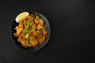 Siyah arka planda pırasa yemek ve limon dilimi