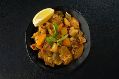 Siyah arka planda pırasa yemek ve limon dilimi