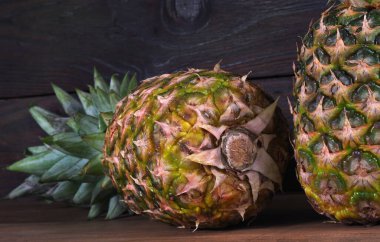 Tahta bir masada olgun ananaslar. Kapat.