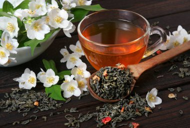 Masada yasemin olan yeşil çay. Yeşil çay yaprakları, yasemin çiçekleri ve bir fincan çay..