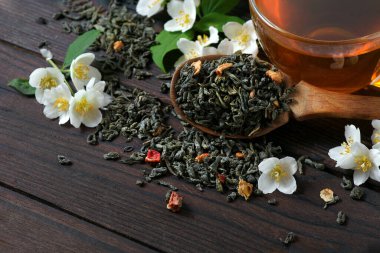 Masada yasemin olan yeşil çay. Yeşil çay yaprakları, yasemin çiçekleri ve bir fincan çay.