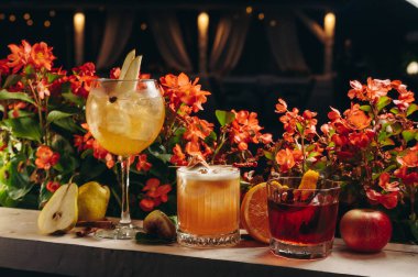 Çiçek arka planında sıcak renklerde üç farklı güzel kokteyl. Kokteyl veya bar menüsü kavramı.
