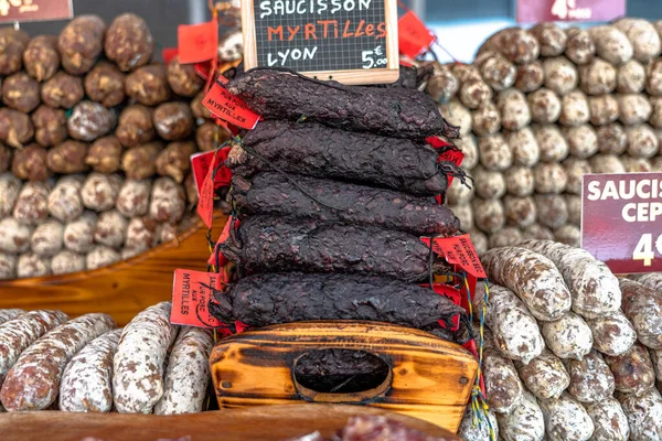 Stacks of dry-cured sausages - saucisson, typically made of pork, or a mixture of pork and other meats. Some variation contains spices and herbs, mushrooms, dried fruits, nuts, or cheese.