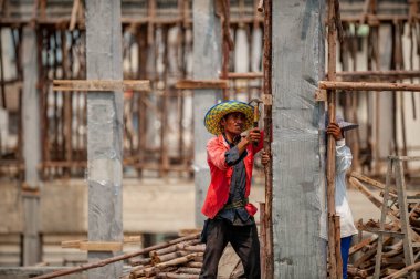 Bangkok, Tayland 5 Eylül 2015: İnşaat işçisi geçici ahşap direkleri beton kolonlara destek olarak çiviledi