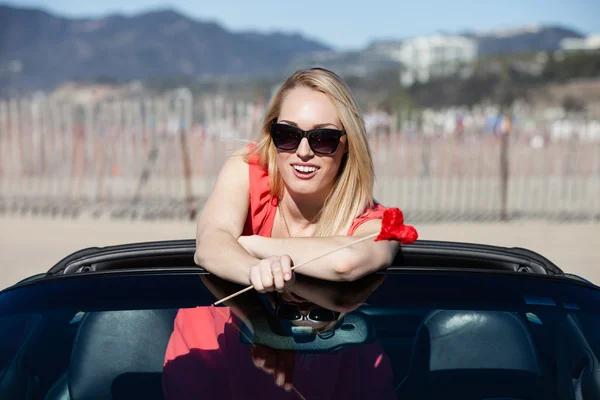Happy Woman with a red heart in a convertible — Stock Photo, Image