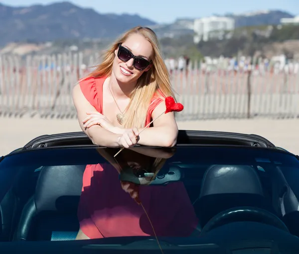 Happy Woman with a red heart in a convertible — Stock Photo, Image