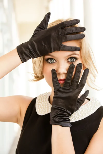 Schöne Frau, die ihre blauen Augen mit schwarzen Handschuhen umrahmt — Stockfoto