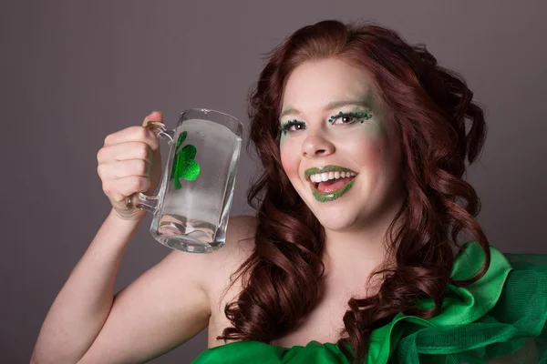 Mulher de cabeça vermelha bebendo de uma caneca com um shamrock no i — Fotografia de Stock