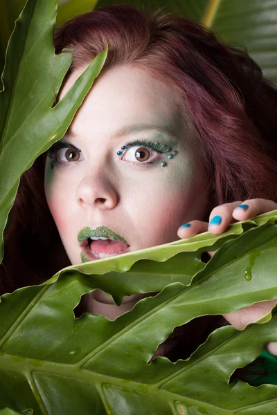 Verrast mooie amazon vrouw in bladeren met plezier groene makeu — Stockfoto
