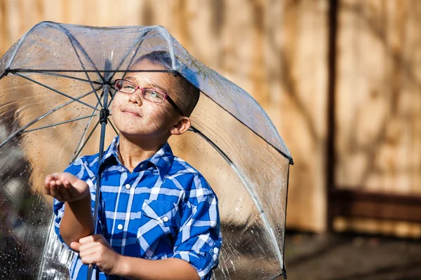 Young boy in a sun shower with umbrella — Stock Photo, Image