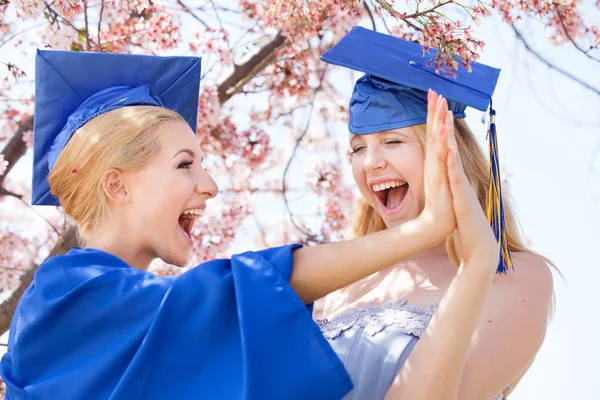 Mulheres graduadas sob flores de cerejeira — Fotografia de Stock