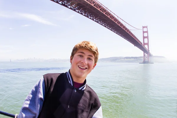 Attraktiver jugendlicher in san francisco unter goldener torbrücke — Stockfoto