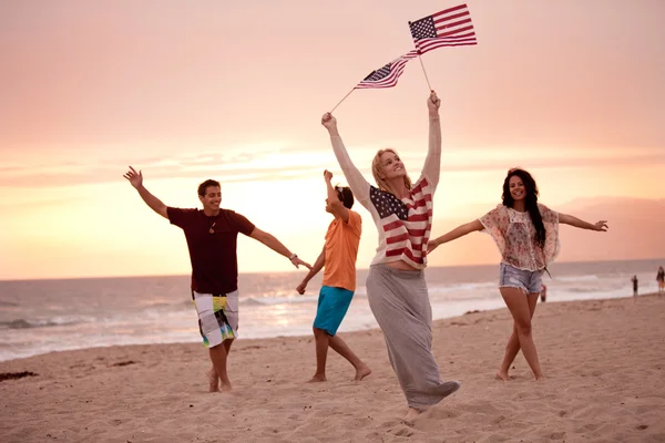 Vänner i tjugoårsåldern dansa på stranden vid solnedgången — Stockfoto