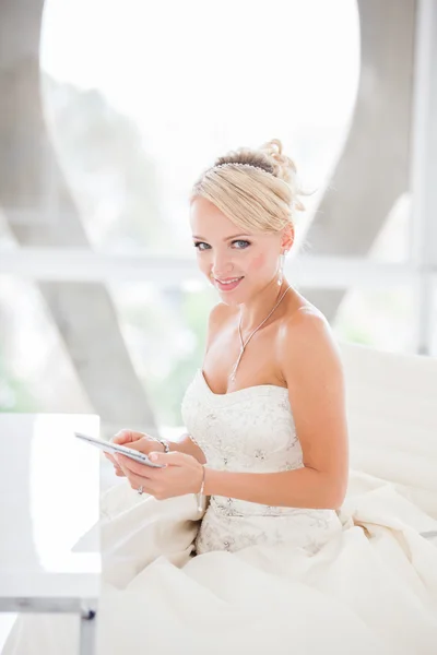 Mooie blonde bruid zitten aan een tafel met een mini tou glimlachen — Stockfoto