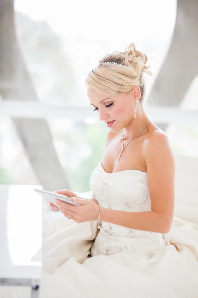 Smiling beautiful blond bride sitting at a table with a Mini tou — Zdjęcie stockowe