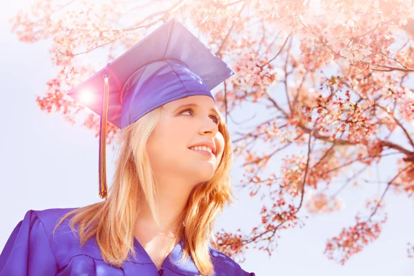 Bastante joven graduado bajo flores de cerezo — Foto de Stock