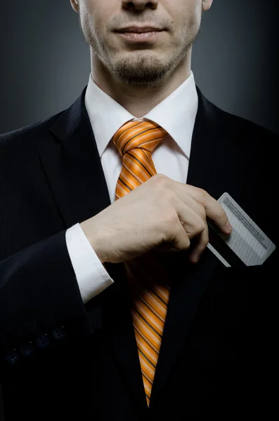 Geschäftsmann in schwarzem Kostüm und orangefarbener Krawatte, Kreditkarte in der Hosentasche, Nahaufnahme — Stockbild Geschäftsmann — Stockfoto
