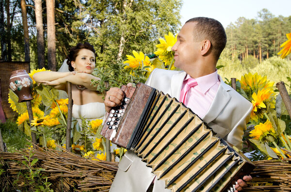 Fiancee listen,  bridegroom play on accordion