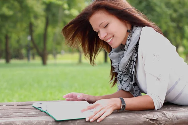 Portrét nádherná bruneta žena čtení knihy v parku — Stock fotografie