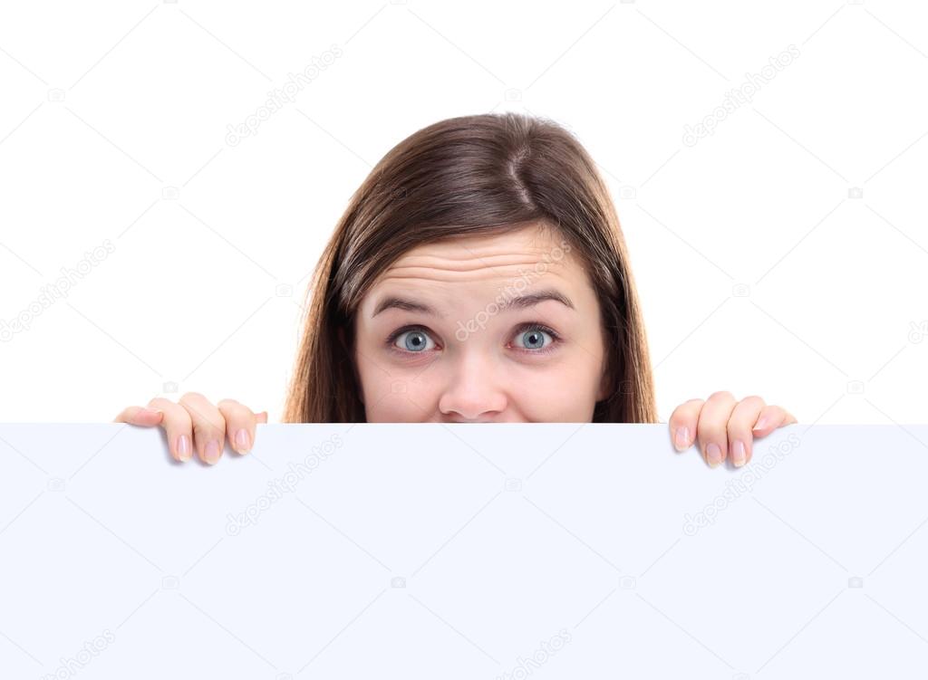 Banner sign woman peeking over edge of blank empty paper billboard with copy space for text. Beautiful woman looking surprised and scared - funny.