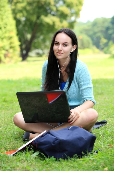 Estudiante universitario sentado en el césped trabajando en la computadora portátil en el campus —  Fotos de Stock