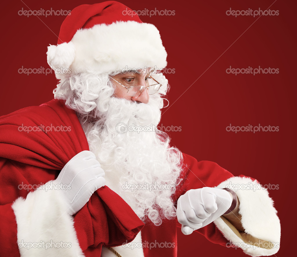 Portrait of Santa Claus with a bag of presents and looking at his watch. Christmas.