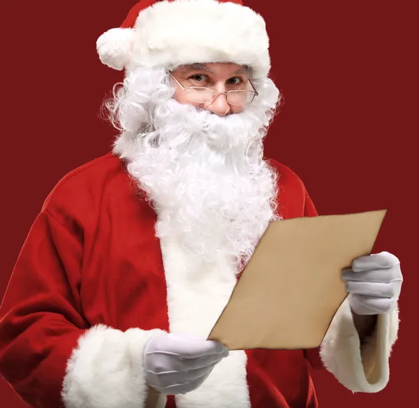 Mutlu Noel Baba 'nın portresi elinde Noel mektubu ve kameraya bakıyor.