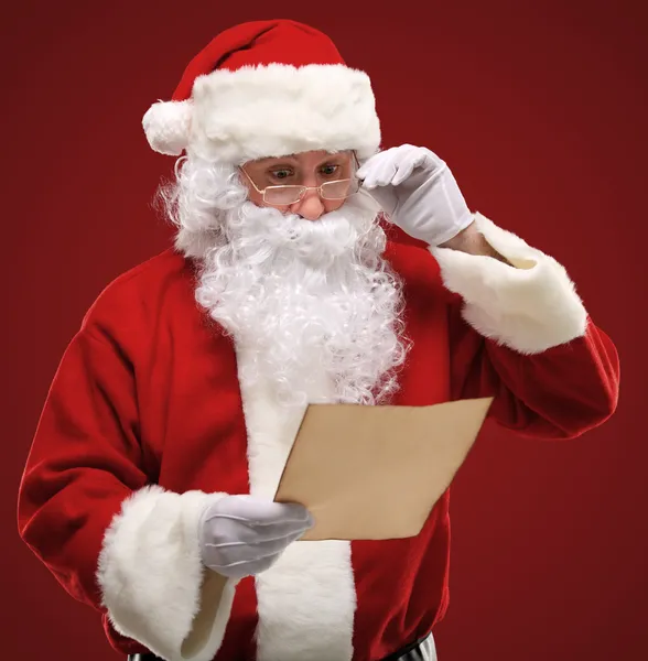 Porträt eines glücklichen Weihnachtsmannes, der einen Weihnachtsbrief in der Hand hält und einen Brief betrachtet — Stockfoto