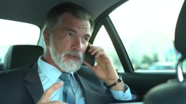 Business Class Car 'da seyahat ederken telefonda konuşan kendine güvenen bir işadamı mı yoksa kendi şoförüyle seyahat ederken pahalı arabasında mı?