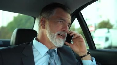 Business Class Car 'da seyahat ederken telefonda konuşan kendine güvenen bir işadamı mı yoksa kendi şoförüyle seyahat ederken pahalı arabasında mı?