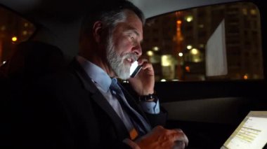 Business Class Car 'da seyahat ederken telefonda konuşan kendine güvenen bir işadamı mı yoksa kendi şoförüyle seyahat ederken pahalı arabasında mı?